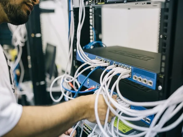 Infokommunikációs hálózatüzemeltető switchet konfigurál és patch-kábeleket köt a rackben